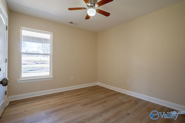 empty room with a ceiling fan, visible vents, light wood-style flooring, and baseboards