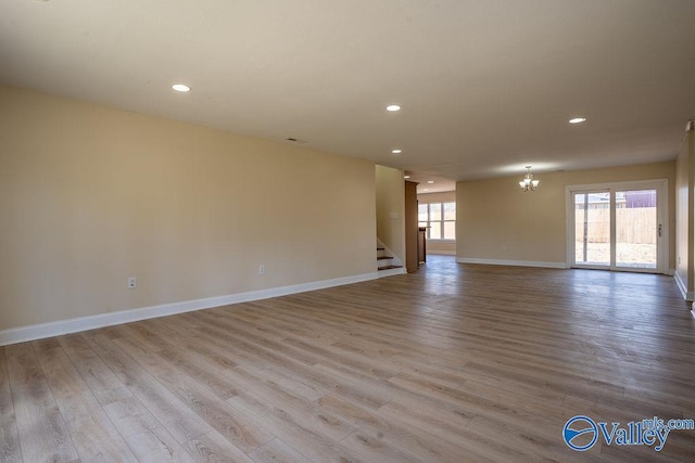 spare room featuring recessed lighting, stairway, wood finished floors, a chandelier, and baseboards