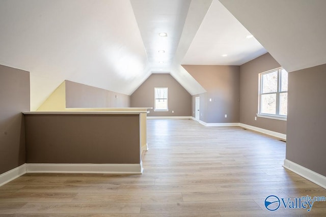 additional living space with lofted ceiling, light wood-style flooring, and baseboards