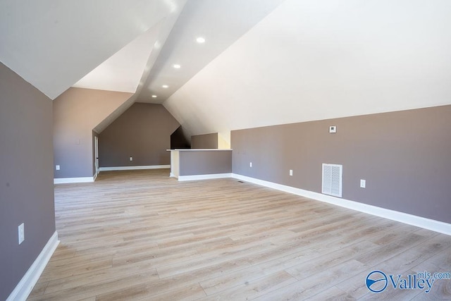 additional living space with lofted ceiling, light wood-type flooring, visible vents, and baseboards