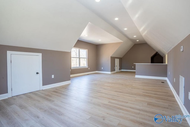 additional living space with light wood-style floors, lofted ceiling, and baseboards