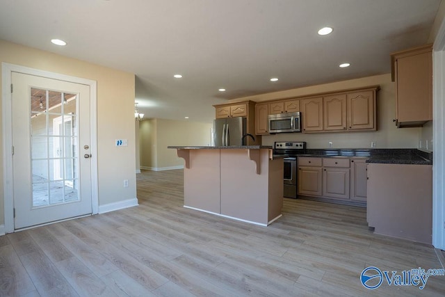 kitchen with stainless steel appliances, light wood finished floors, a kitchen bar, and recessed lighting