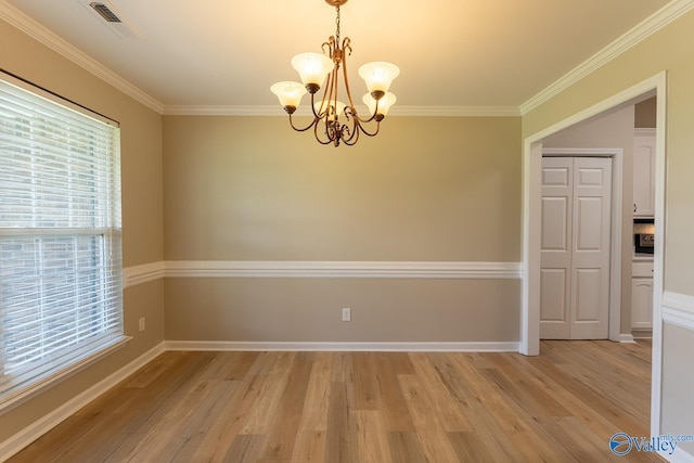 unfurnished room featuring light wood-type flooring, crown molding, and a notable chandelier