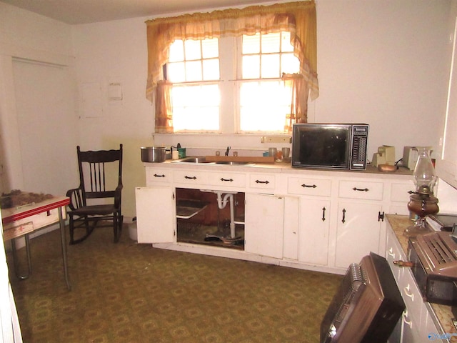 kitchen with white cabinets, sink, and black microwave