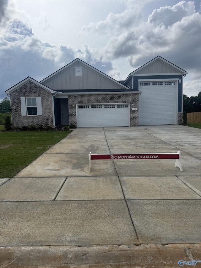 view of front of property with an attached garage, concrete driveway, a front yard, brick siding, and board and batten siding