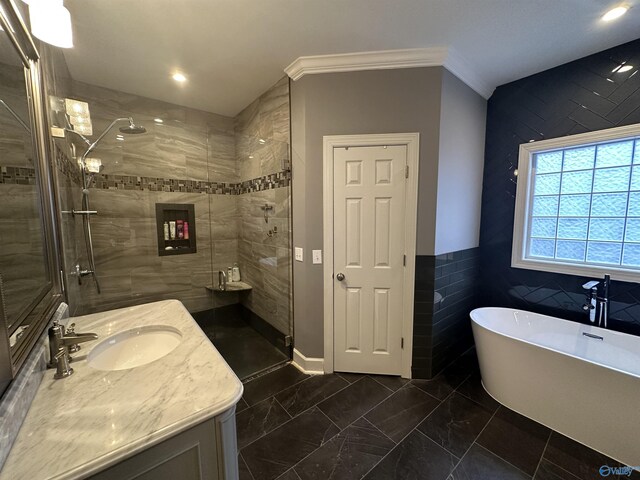 bathroom featuring plus walk in shower, vanity, tile walls, and ornamental molding