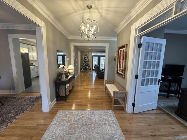 hallway featuring hardwood / wood-style floors, an inviting chandelier, french doors, and crown molding