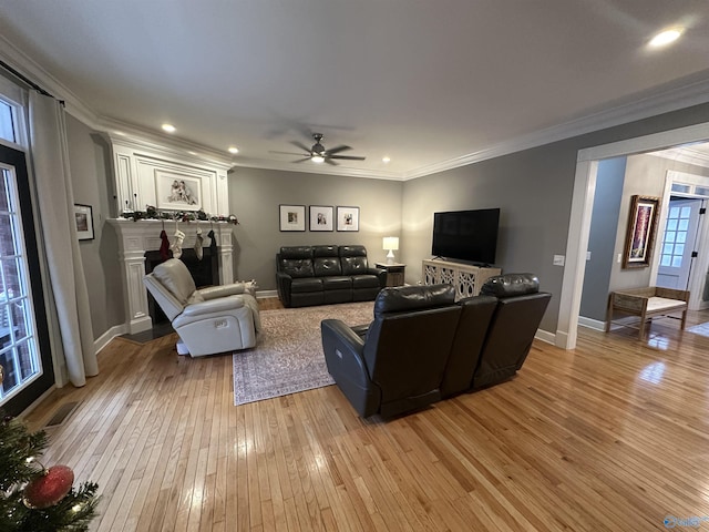 living room with crown molding, ceiling fan, and light wood-type flooring