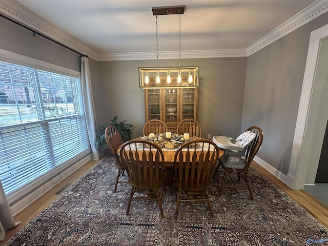 dining space featuring crown molding, an inviting chandelier, and hardwood / wood-style flooring