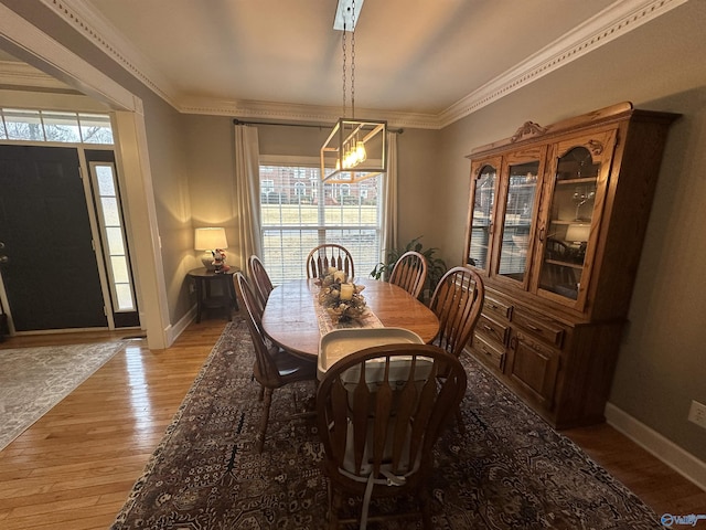 dining room featuring a chandelier, light hardwood / wood-style flooring, and crown molding