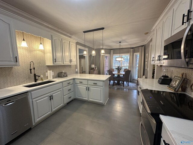 kitchen with pendant lighting, white cabinets, sink, kitchen peninsula, and stainless steel appliances