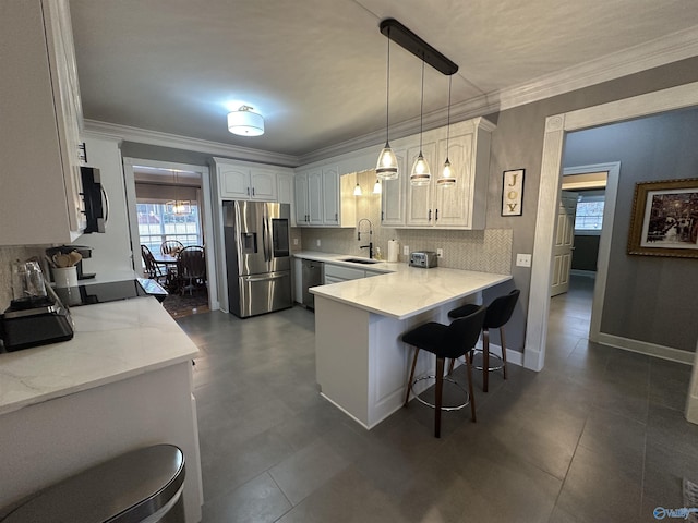 kitchen featuring kitchen peninsula, appliances with stainless steel finishes, sink, decorative light fixtures, and white cabinets