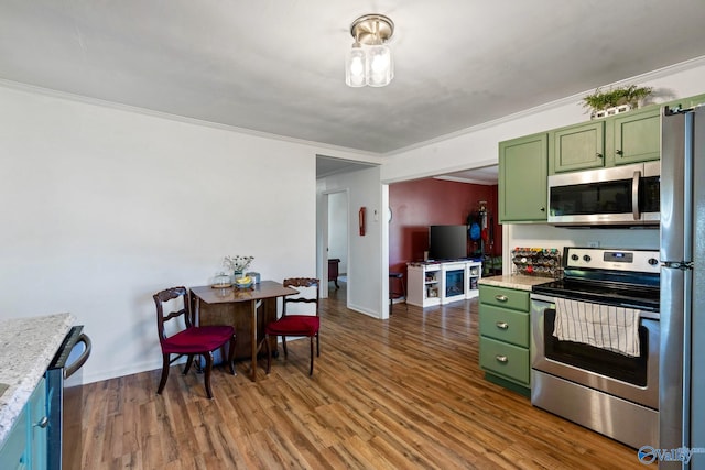 kitchen with stainless steel appliances, crown molding, green cabinetry, light stone counters, and dark hardwood / wood-style flooring