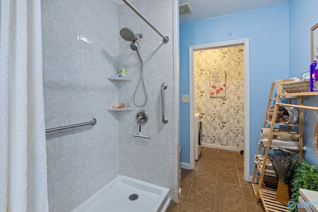 bathroom featuring a textured ceiling, washer / clothes dryer, tile patterned flooring, and walk in shower