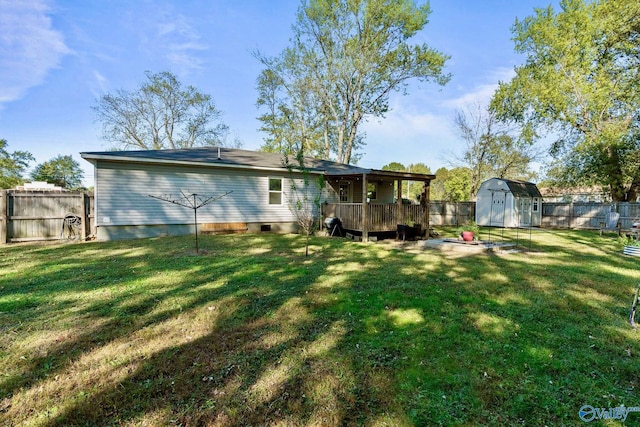 back of house with a yard, a storage shed, and a wooden deck