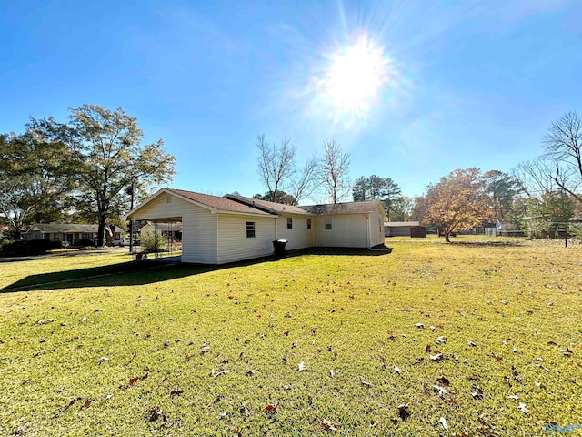 rear view of property with a carport and a lawn