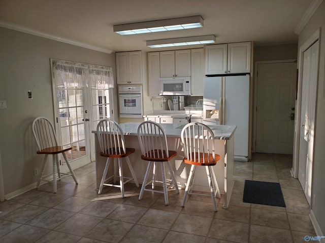 kitchen with french doors, white appliances, ornamental molding, and a kitchen breakfast bar