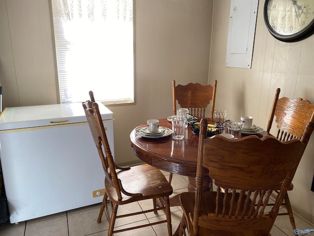 dining space featuring electric panel, wood walls, and light tile patterned floors