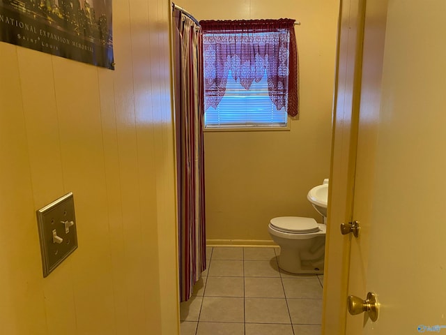 bathroom featuring toilet, tile patterned floors, and wooden walls