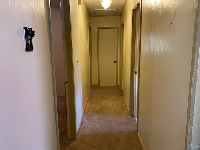 hallway featuring light colored carpet and a textured ceiling