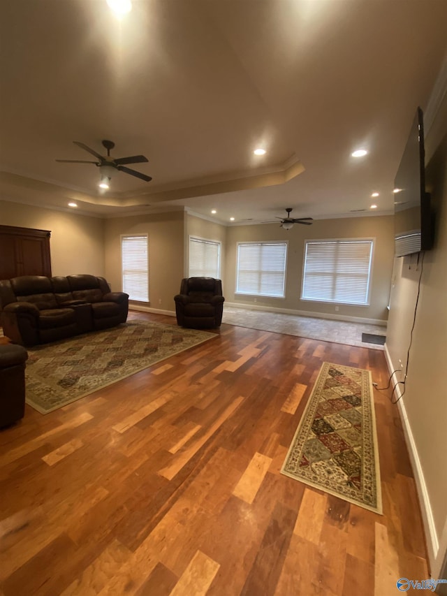 living room with a tray ceiling, hardwood / wood-style flooring, and crown molding