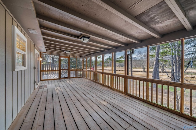 unfurnished sunroom featuring a healthy amount of sunlight and beam ceiling