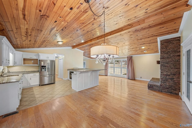 kitchen featuring lofted ceiling, stainless steel fridge with ice dispenser, ornamental molding, pendant lighting, and white cabinets