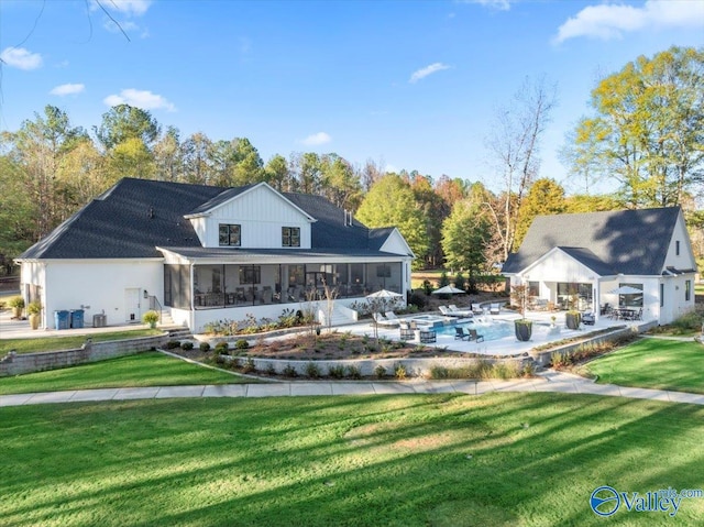 rear view of property featuring a sunroom, a pool, and a lawn