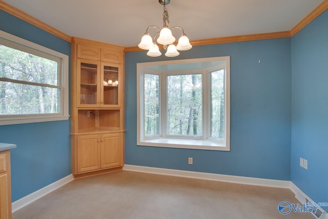 unfurnished dining area with a healthy amount of sunlight, ornamental molding, light carpet, and a chandelier