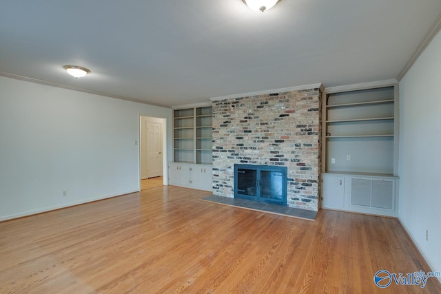 unfurnished living room featuring crown molding, built in features, light hardwood / wood-style floors, and a brick fireplace