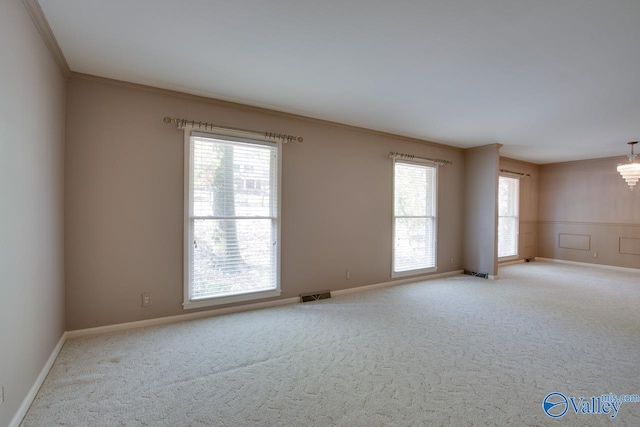 spare room featuring carpet flooring, a chandelier, and crown molding