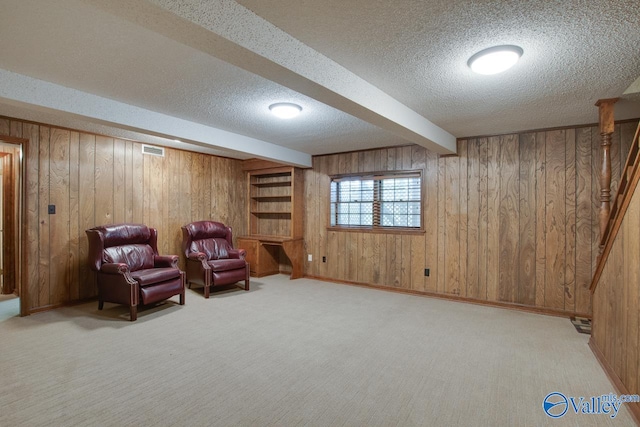 living area with light carpet, a textured ceiling, and wood walls