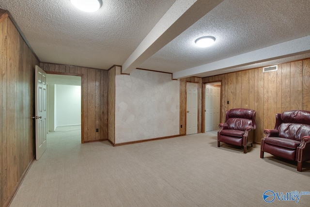 living area with wood walls, light colored carpet, and a textured ceiling