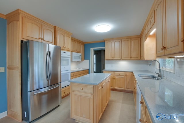 kitchen featuring light brown cabinetry, backsplash, white appliances, sink, and a kitchen island