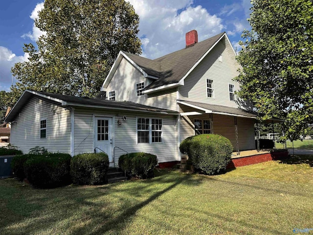 view of home's exterior with entry steps, a yard, and a chimney