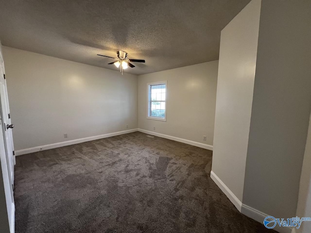 spare room with a textured ceiling, dark colored carpet, ceiling fan, and baseboards