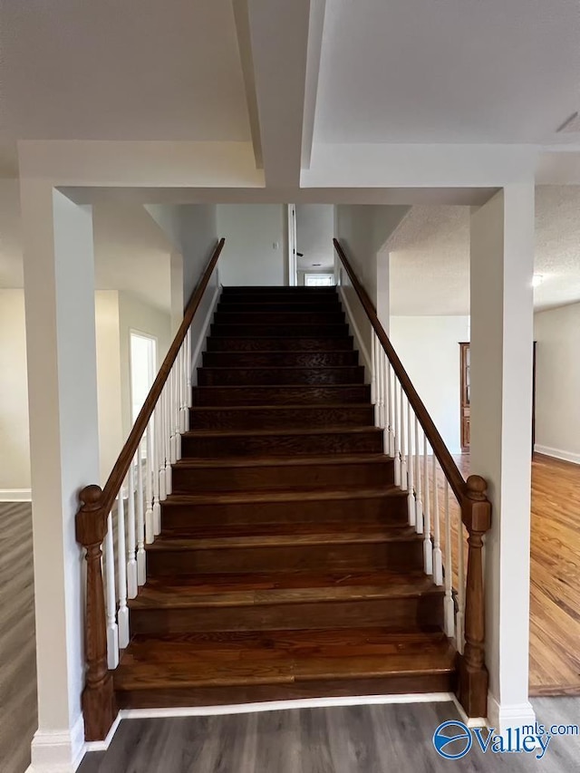 staircase featuring baseboards and wood finished floors