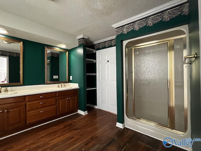 full bath featuring a sink, a shower stall, a textured ceiling, and wood finished floors