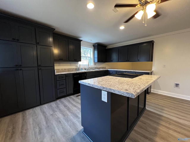 kitchen with black dishwasher, a kitchen island, dark cabinets, light wood-type flooring, and a sink