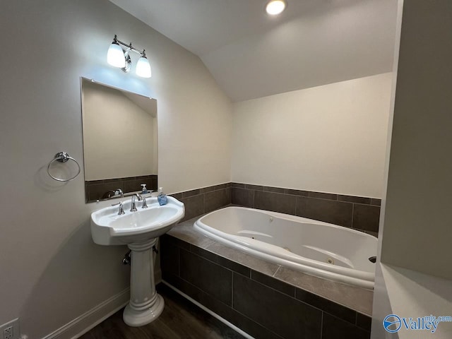 full bath with a tub with jets, vaulted ceiling, and wood finished floors