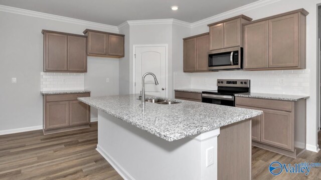 22401 Westminster Dr, Athens, AL 35613 - kitchen with stainless steel appliances, a sink, wood finished floors, decorative backsplash, and a kitchen island with sink