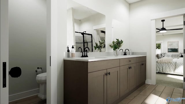 full bathroom with double vanity, baseboards, ceiling fan, a sink, and ensuite bath