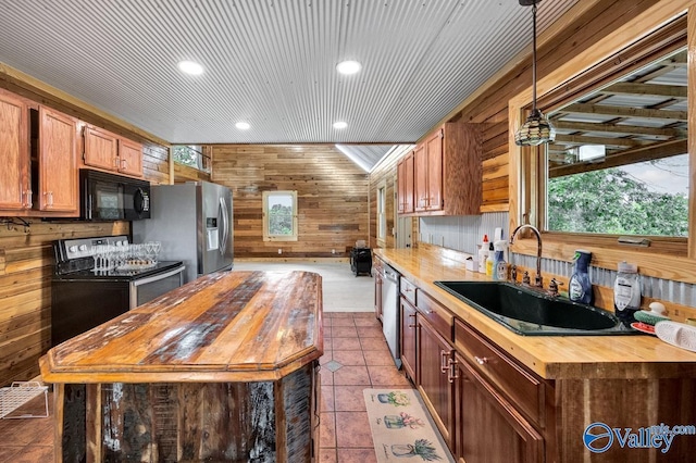 kitchen featuring wood counters, sink, decorative light fixtures, appliances with stainless steel finishes, and wooden walls