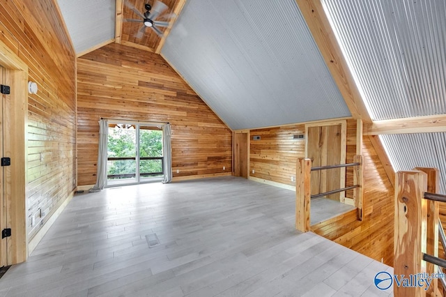 bonus room with vaulted ceiling, light hardwood / wood-style flooring, ceiling fan, and wood walls