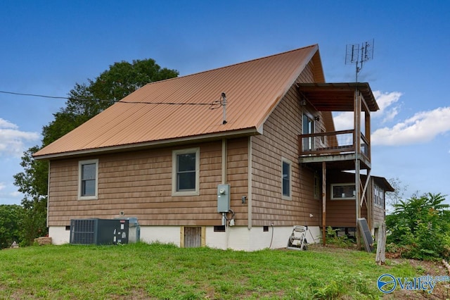 back of house featuring a balcony, a yard, and central AC