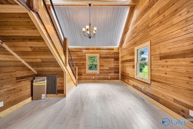 bonus room featuring a chandelier, vaulted ceiling, light hardwood / wood-style flooring, and wood walls