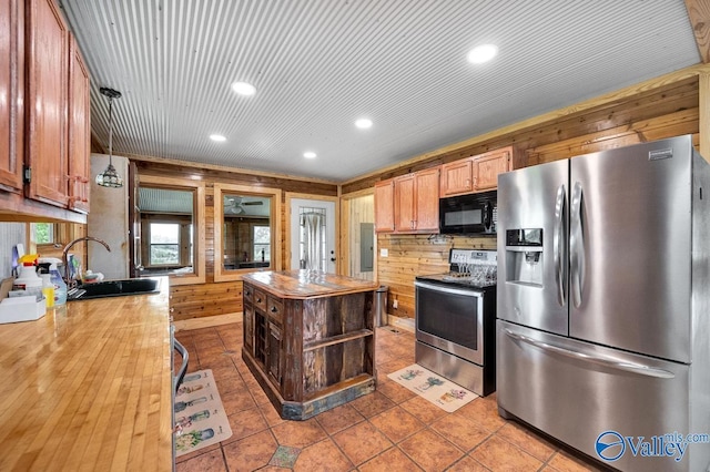 kitchen with sink, light tile patterned floors, wooden walls, and stainless steel appliances