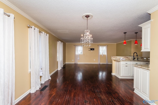 kitchen with dark wood-type flooring, white cabinets, sink, ornamental molding, and pendant lighting