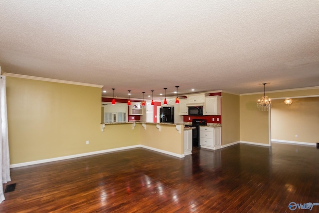 unfurnished living room with ornamental molding, an inviting chandelier, a textured ceiling, and dark hardwood / wood-style floors