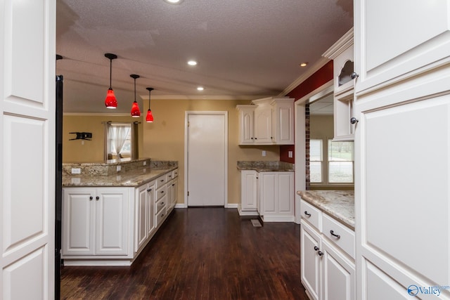 kitchen with white cabinets, a textured ceiling, ornamental molding, dark hardwood / wood-style floors, and decorative light fixtures